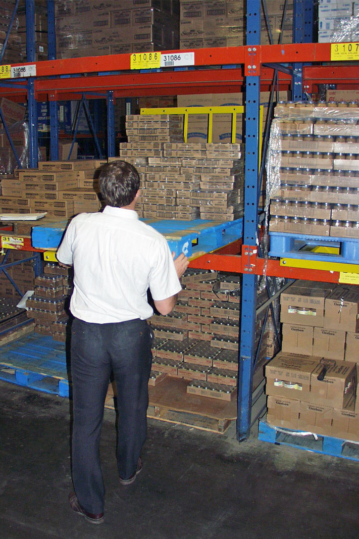 A worker picks product from Frazier's Glide 'N Pick® pallet rack cart.
