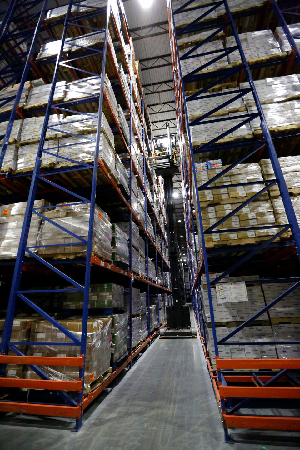 A fork truck travels down aisle in a VNA Push Back Racking System.